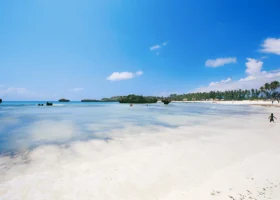 Veduta panoramica sull'oceano Indiano turchese e trasparente dalla costa del Barracuda Inn Resort, con la caratteristica battigia di sabbia chiara e fine lambita da piccole onde calme sotto un cielo sereno.