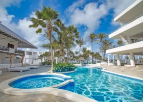 La grande piscina d'acqua dolce del Barracuda Inn Resort a Watamu, caratterizzata da acque limpide e azzurre, circondata da lettini prendisole, ombrelloni in paglia e dagli edifici del resort con i tradizionali tetti alti in makuti africano.