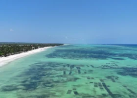 Spettacolare veduta aerea panoramica della lunghissima spiaggia bianca del Bluebay Beach Resort lambita dalle sfumature turchesi dell'oceano