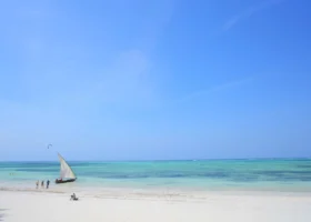 Scorcio ravvicinato della spiaggia bianca del resort con una tipica imbarcazione a vela dhow ormeggiata sul bagnasciuga in una giornata di sole