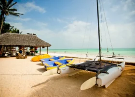 Catamarano e canoe posizionati sulla sabbia dorata del Bluebay Beach Resort davanti al centro escursioni e sport acquatici