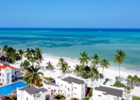 Veduta aerea delle ville bianche stile arabo, della piscina e della spiaggia di sabbia finissima del Marijani Beach Resort davanti all'oceano turchese