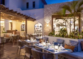 Tavoli apparecchiati sotto un pergolato in legno illuminato la sera nel cortile esterno del ristorante del Marijani Beach Resort