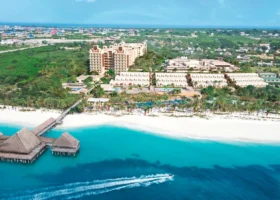 Veduta aerea della spiaggia bianca e dell'intero complesso dell'Hotel Riu Jambo a Nungwi con il mare cristallino sfumato di azzurro e una moto d'acqua in transito