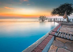 Grande piscina a sfioro del Royal Zanzibar Beach Resort che si fonde con il mare calmo durante un tramonto dalle sfumature arancioni