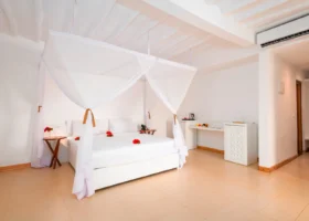 Camera da letto deluxe con letto a baldacchino e zanzariera presso il Sandies Baobab Beach Resort a Zanzibar