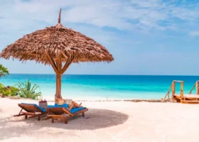 Turista si rilassa su un lettino sotto l'ombrellone di paglia sulla spiaggia bianca del Sandies Baobab Beach Resort