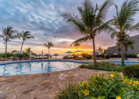 Piscina del resort Sandies Baobab Beach circondata da palme e vegetazione tropicale al tramonto a Nungwi