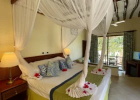 Interno di una camera da letto del Sultan Sands Island Resort con un grande letto matrimoniale dotato di zanzariera a baldacchino e soffitto con travi in legno scuro