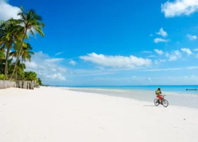 Un uomo in bicicletta sulla lunghissima e bianchissima spiaggia di Kiwengwa davanti al mare turchese del Sultan Sands Island Resort