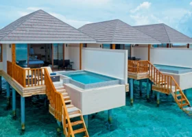 Ville overwater di Brennia Kottefaru con piscina privata a sfioro, terrazza in legno e scaletta che scende direttamente nella laguna turchese dell'Atollo di Raa, alle Maldive, con tetto in tegole e vista aperta sull'Oceano Indiano.